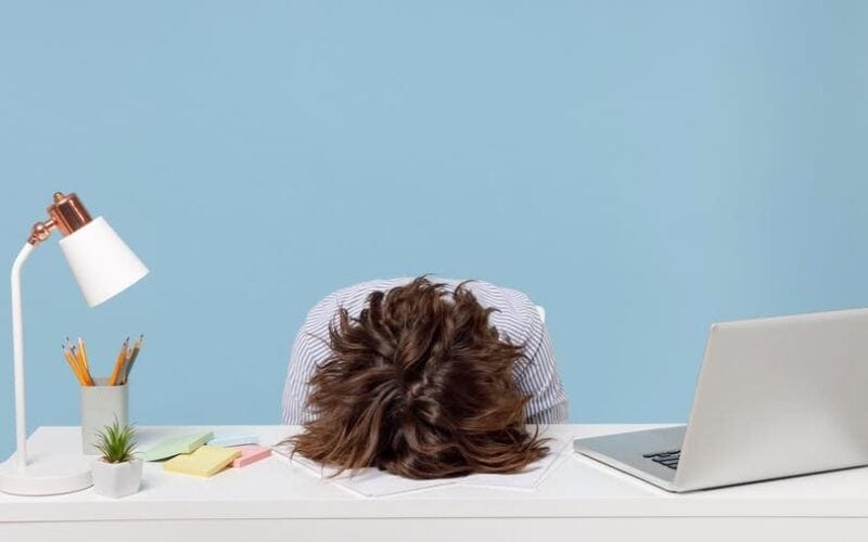 Người làm việc mệt mỏi trên bàn làm việc, biểu tượng stress công việc.